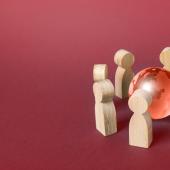 Wooden humanoid figures gathered around a small globe. 