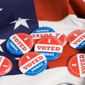several i voted today buttons on an American flag