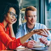 two business people discussing something on a laptop