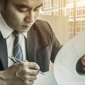 a man in a suit looking at a document and holding a pen
